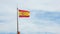Spanish flag waving in the wind against blue sky and white clouds. National symbol of Spain