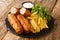 Spanish flamenquines are a slice of pork, with jamon rolled into a tube breaded and fried served with French fries closeup in the