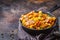 Spanish migas with pork and green onions in cast-iron pan on dark background
