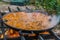 Spanish Paella cooked on natural log fire and coal in a traditional fireplace.