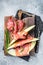 Spanish Tapas Jamon Iberico with goat cheese, melon and honey on a wooden board. Gray background. Top view