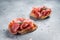 Spanish Tapas with tomatoes and cured Slices of jamon iberico ham, fresh toasts. Gray background. Top view