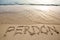 Spanish word perdÃ³n written in the sand