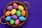 Sparkling glittering colored candy Easter eggs in a wicker basket, top view