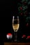 Sparkling wine in the champagne glass and red caviar against the black background