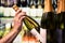 Sparkling wine from shelf of alcohol store. Bottle in hand. Liquor shop. Prosecco or champagne display in spirits market.