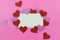 Sparkly pink and red hearts surround a parchment paper tage on a bright pink background for Valentine`s Day in February. Copy spa