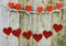 Sparkly red hearts handing from decorated clothespins by string in front of rustic wooden background for Valentine`s Day.