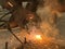 Sparks from a welding torch during the work of the welder. The master solders a metal rod with a tool. Worker cuts reinforced