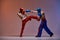 Sparring of two fighting guys in boxing gloves during battle in red blue light, martial arts, mixed fight concept