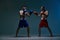 Sparring of two fighting males boxers during battle in blue studio light, martial arts, mixed fight concept