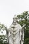 A sparrow perches on a statue of a priest.