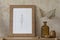 Sparse boho interior of living room with brown mock up poster frame, leaves in vase and elegant accessories. Home staging.