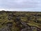Sparse landscape with lava field with rocky fissures covered by green moss and lichens near Grindavik, Reykjanes, Iceland.