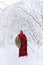 Spartan warrior walks through winter forest in long red cape.