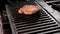 Spatula flip hamburger patty on the grill - close up, slow motion