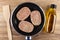 Spatula, raw pork cutlets in frying pan, vegetable oil on table. Top view