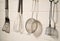 Spatula, whisk, masher and strainer hanging against white wall in restaurant or home kitchen. Kitchen utensils made of