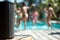 speaker on a poolside deck with blurry figures dancing in swimsuits