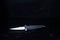 Spear-shaped knife on a black background. Black background and splashes of water