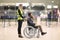 Special assitance worker inside an airport building pushing a male passanger in a wheelchair