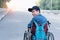 special child on wheelchair wearing blue shirt and cap with backpack learn how to use wheelchairs on public street