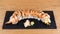 Special Uramaki, rice roll stuffed with shrimp tempura, green salad, avocado, covered with grilled salmon, seasoned with black and