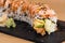 Special Uramaki, rice roll stuffed with shrimp tempura, green salad, avocado, covered with grilled salmon, seasoned with black and