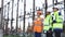 Special workers planning a project at a power station. Three engineers discussion near power lines. Electric industry