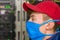 The specialist is in the datacenter during the quarantine. Portrait of a masked teenager in close-up. A technician in a red cap