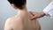 Specialist examining female back, holding her shoulder, scoliosis treatment