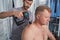 Specialist massages back with percussion tool of man with disability