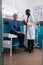 Specialist physician doctor holding pills bottle explaining medication treatment to pensioner man patient