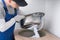 A specialist in protective clothing and gloves, installs a metal sink with an assembled white sewer pipe, in the opening of the