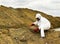 Specialist in protective clothing takes a sample of the soil in