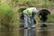 A specialist in a protective suit holds a suitcase with equipment in his hands and measures the level of water pollution in the