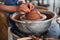 Specialist shaping bowl rims with bare hands on throwing wheel