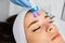 Specialist uses microcurrent massage device on female forehead for removing wrinkles