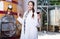 Specialist in white coat examines glass of wine on the background of barrels for fermentation