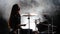 Specially trained girl plays the drums. Black smoke background. Silhouette