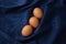 Speckled brown eggs food styling on velvet blue organic crumpled texture tea towel, napkin, fabric abstract background.