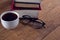 Spectacles, black coffee and book stack on wooden table