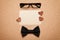 Spectacles, bowtie and empty paper blank in Happy Fathers Day, cork board background, top view, flat lay