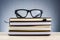 Spectacles on stack of books over beautiful gradient background with reverberation