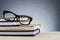 Spectacles on stack of books over beautiful gradient background with reverberation