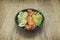 Spectacular black poke bowl with smoked salmon slices, cucumber slices, half rolled avocado, lettuce sprouts