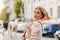 Spectacular blonde woman with hair waving hanging out alone carrying newspaper home. Outdoor portrait of interested lady