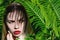 Spectacular bright portrait of a beautiful girl with a fern branch near her face. The concept of natural beauty and