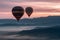 Spectacular dawn/dusk scene with hot air balloons above mist covered valleys and colorful mountain backdrop