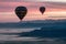 Spectacular dawn/dusk scene with hot air balloons above mist covered valleys and colorful mountain backdrop